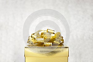 Close up Golden present box with big bow at bokeh white blur background, Leave space on top to adding your content